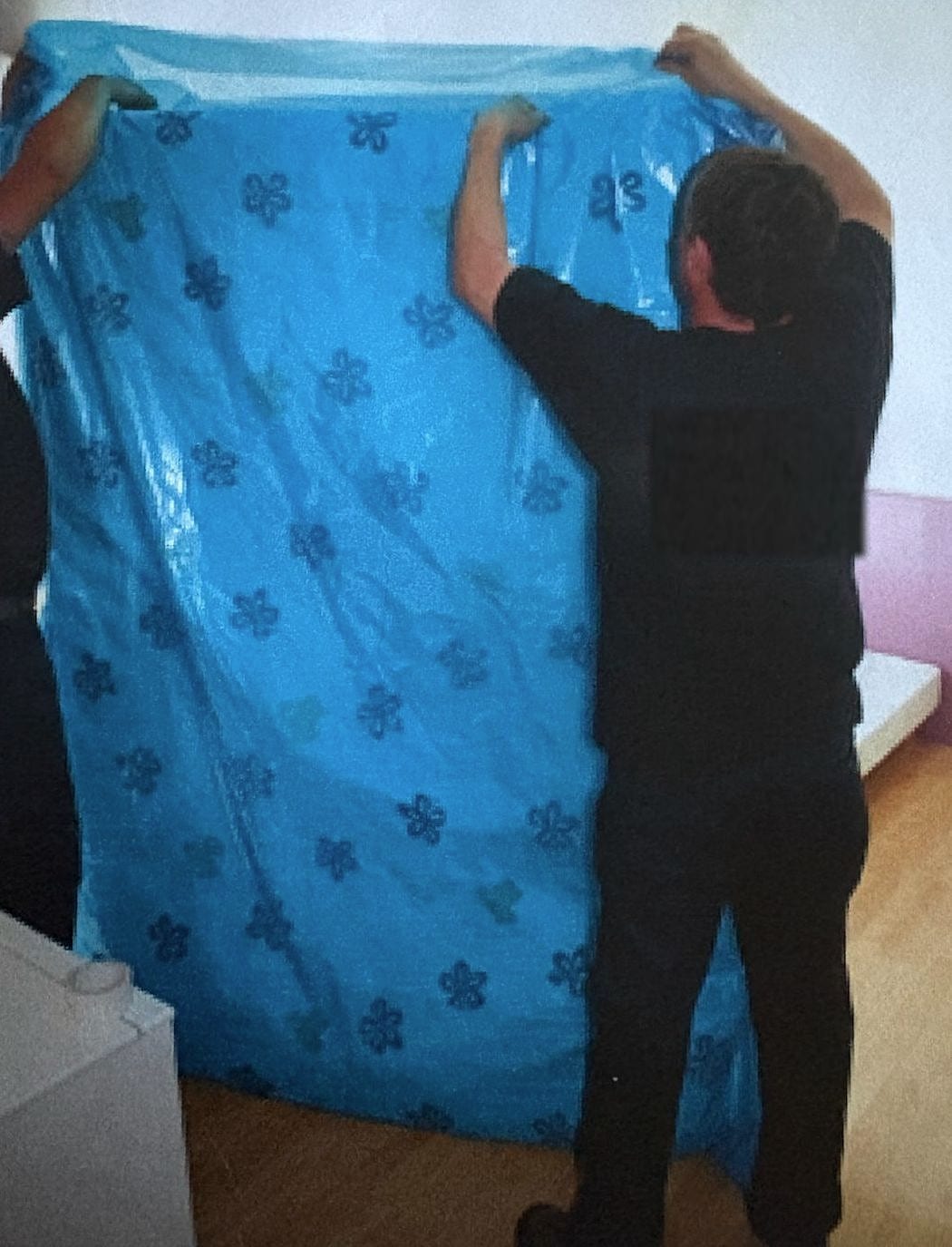 Déménageurs glissant un matelas dans une housse de protection
